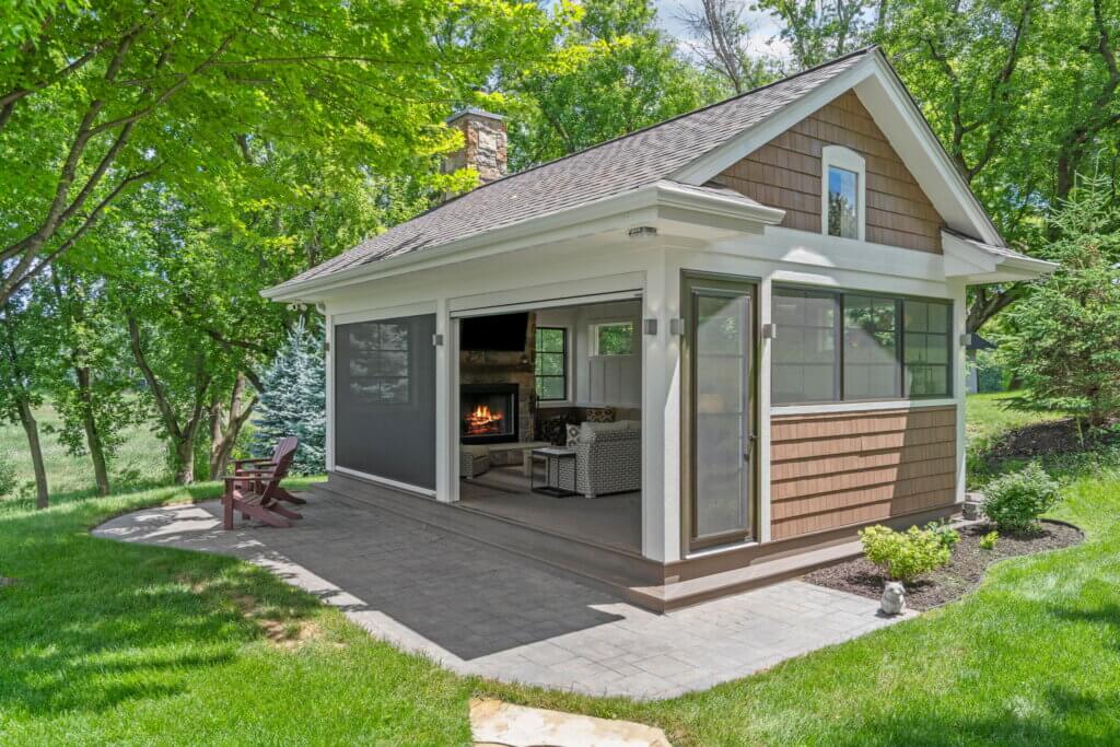 Completed detached three-season porch with large screened openings, fireplace, and outdoor seating.