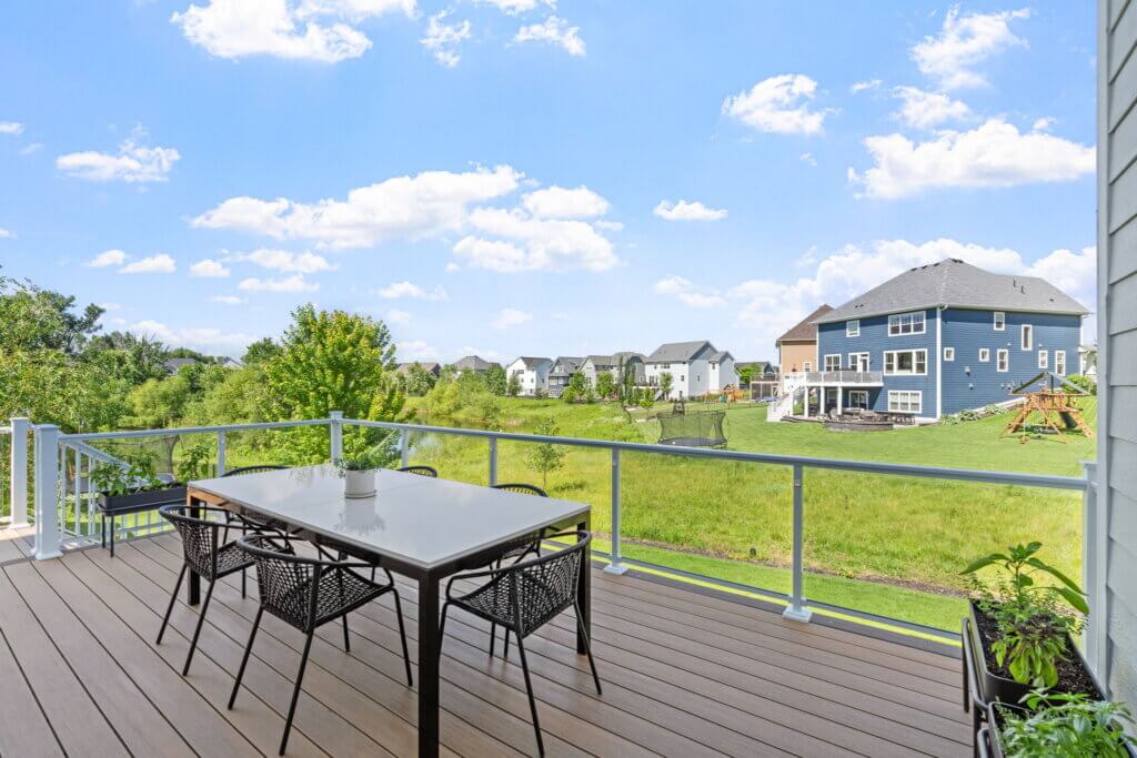 Completed composite deck with glass railing overlooking the backyard.