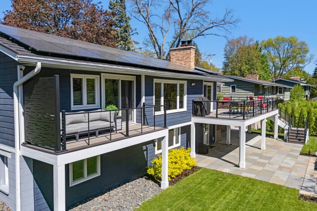 Completed elevated composite deck with cable railing and patio underneath.
