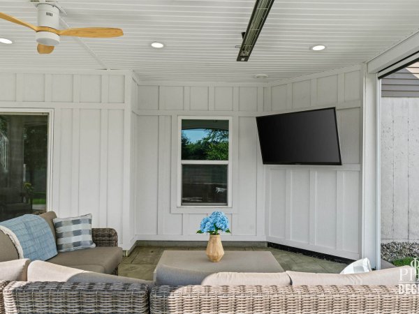 Covered outdoor living area beneath The Oakview Deck with TV wall, ceiling fan, recessed lights, and infrared heater.